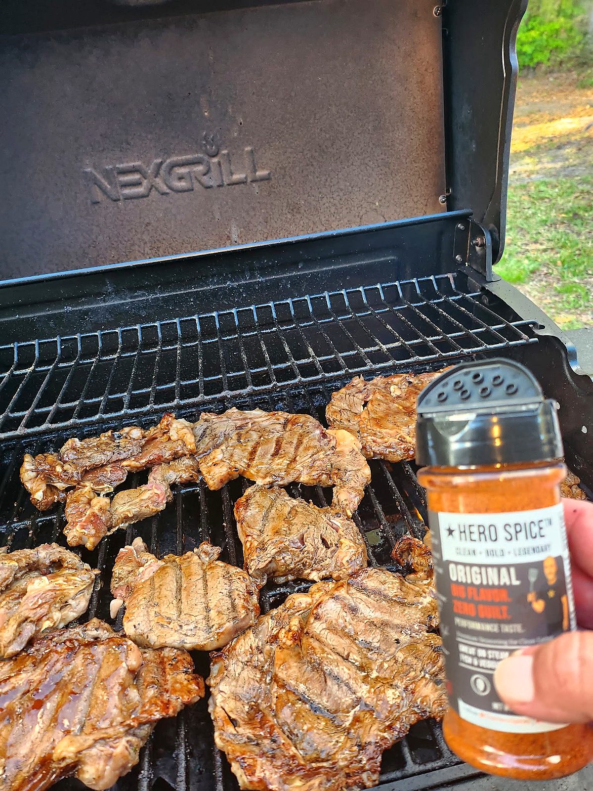 Chicken on a grill with a Hero Spice Original shaker nearby