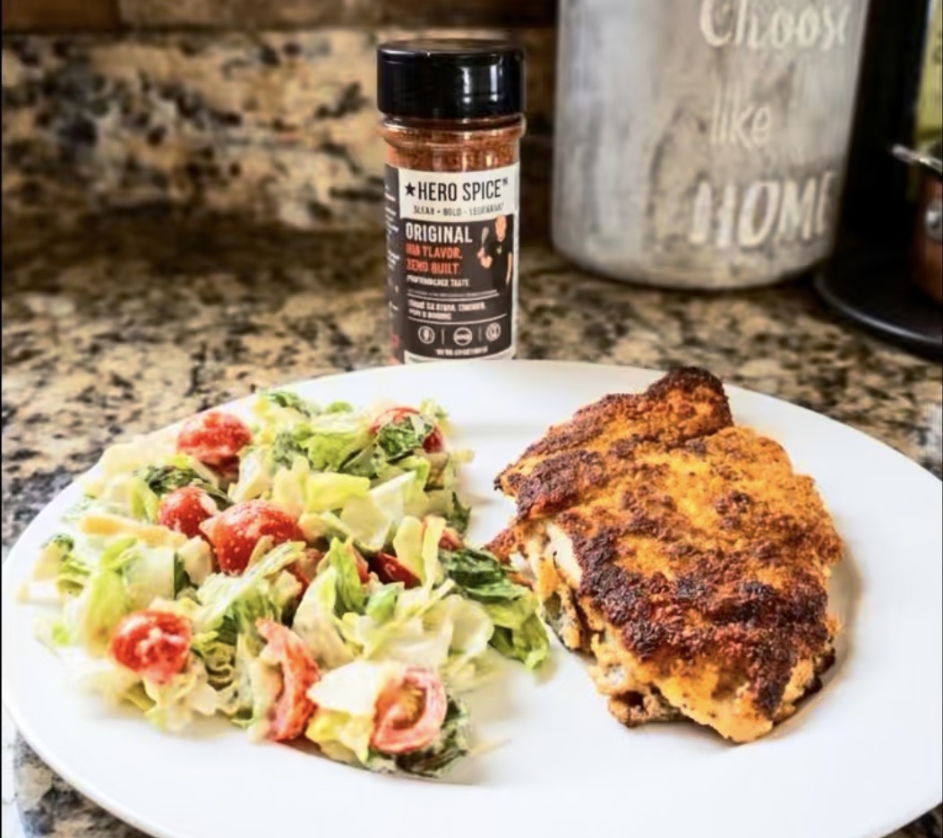 Real Hero Spice Original shaker beside chicken and salad at home