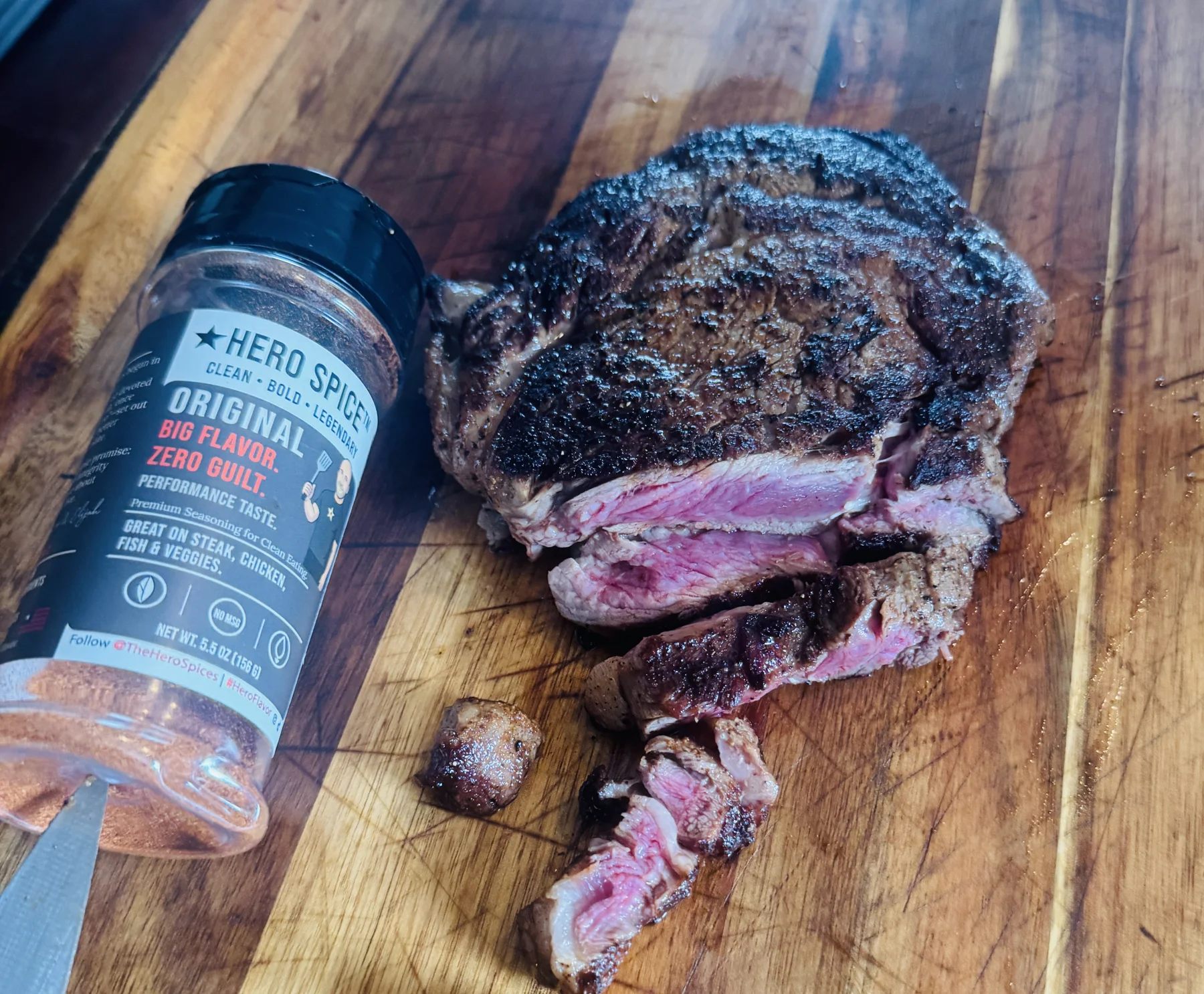 Hero Spice Original shaker beside sliced steak on a cutting board